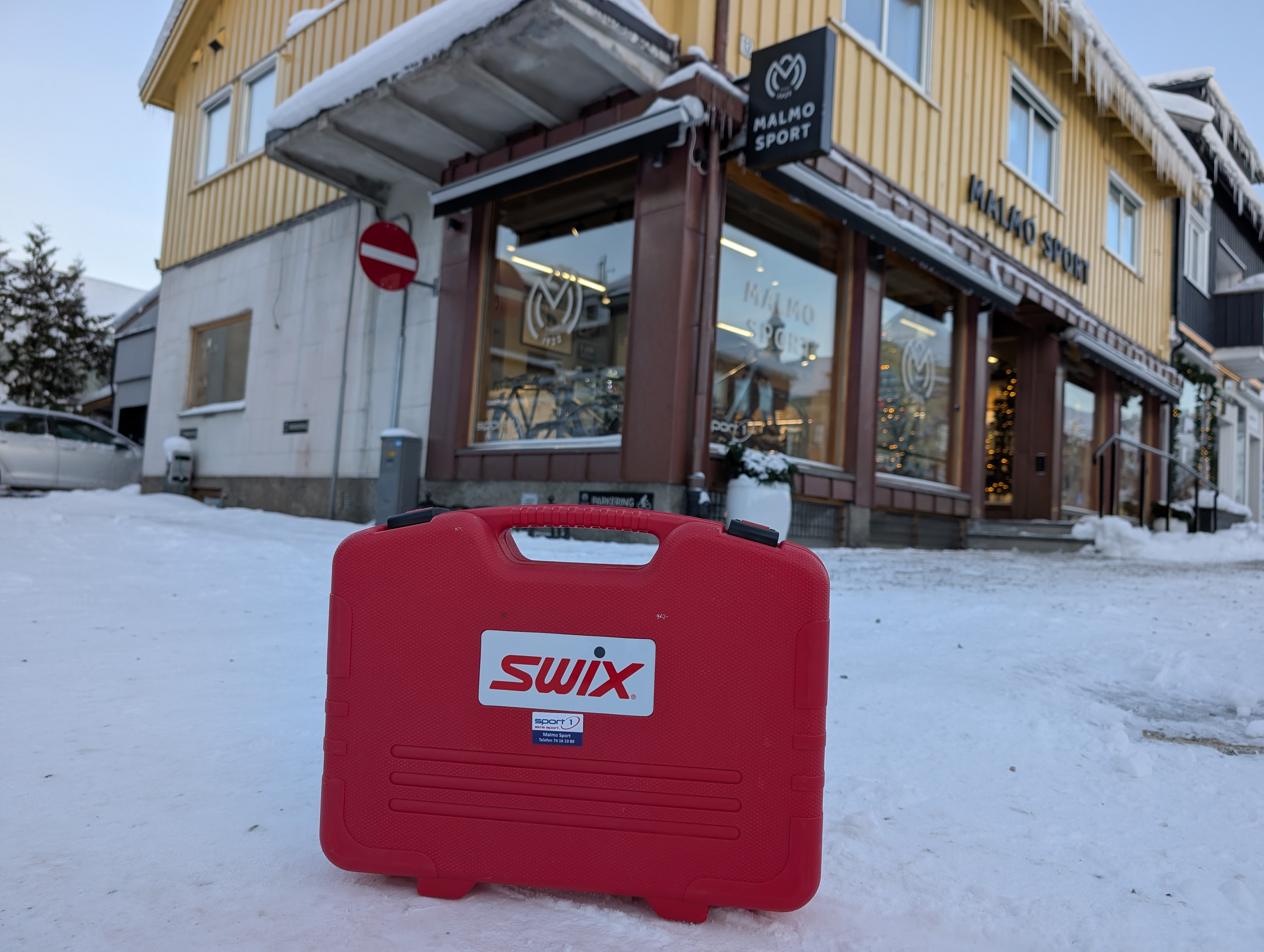 Smørekoffert som står i snøen foran en butikk 